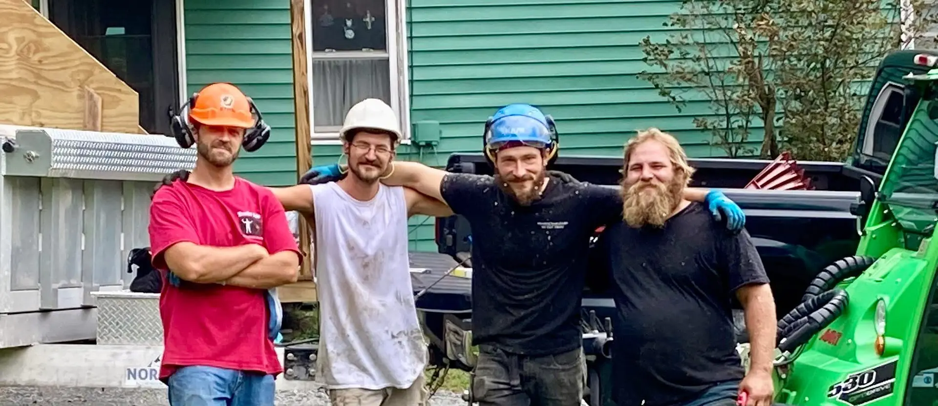 Four Branch Managers crew members in helmets smiling outside a green house